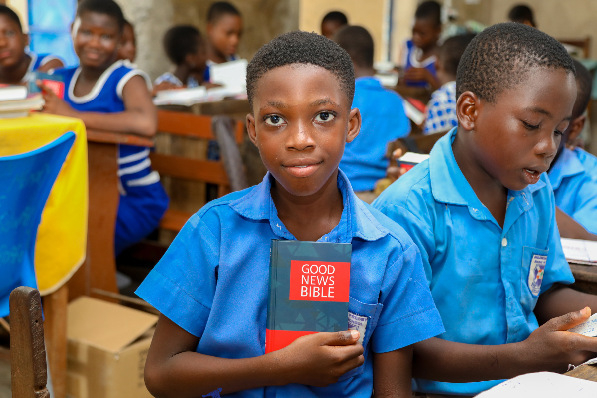 Adom proudly holds his Bible.