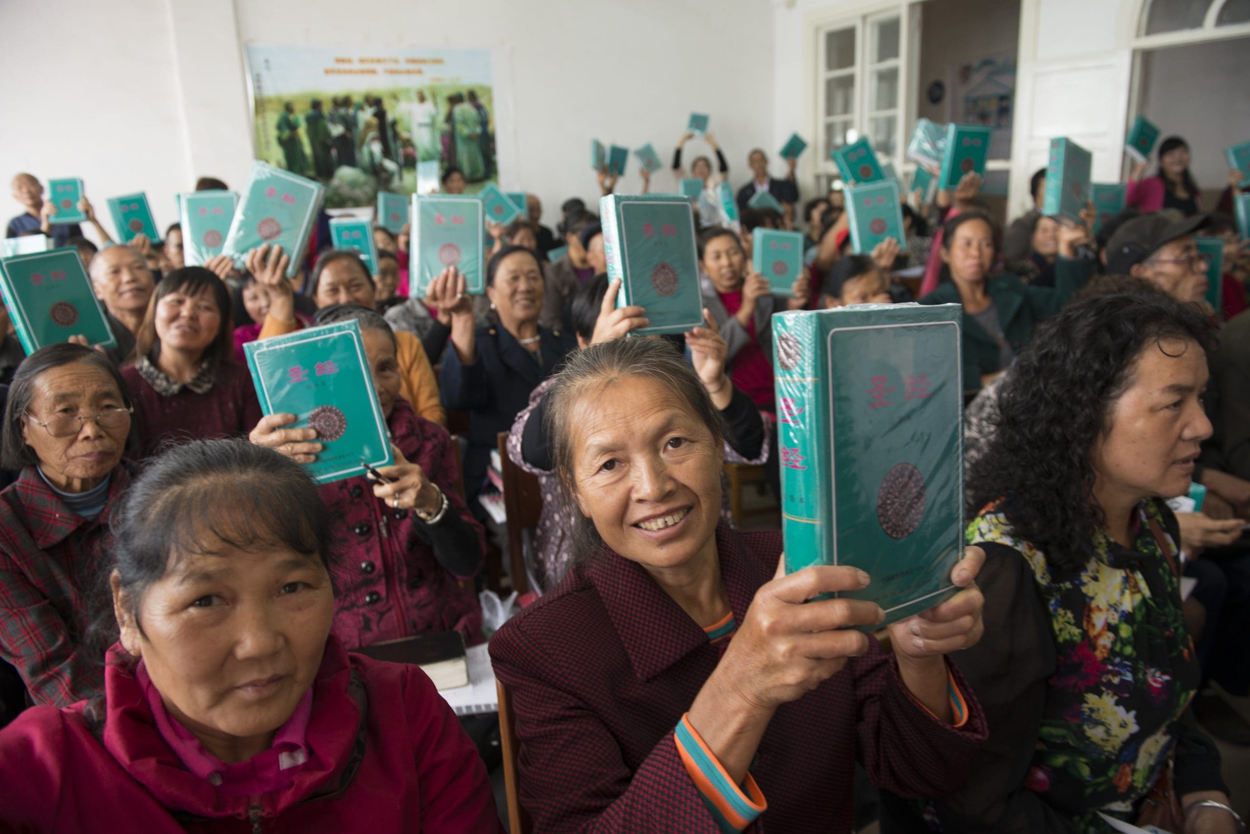 Chinese Christians show joy at receiving Bibles during a Bible distribution at a church.